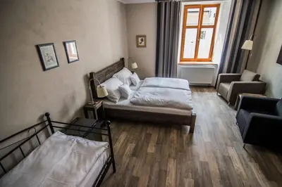 a bedroom with two beds and a couch and a chair at Pension Viktorin in Poděbrady