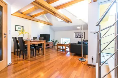 a dining room and living room with a table and chairs at Attic Apartment by Wenceslas Square in Prague