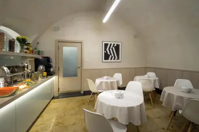a restaurant with white tables and chairs and a kitchen at Clementin in Prague