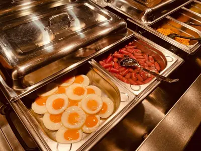a buffet line with trays of eggs and tomatoes at Hotel Askania in Prague