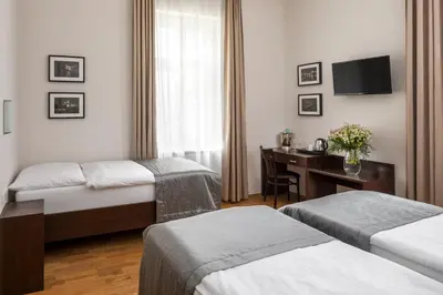a hotel room with two beds and a desk at Hotel Unique in Prague