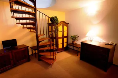 a living room with a spiral staircase and a desk at Hotel U Kříže in Prague