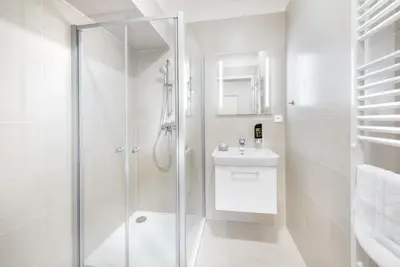a white bathroom with a shower and a sink at DownTown Suites Belohorska in Prague