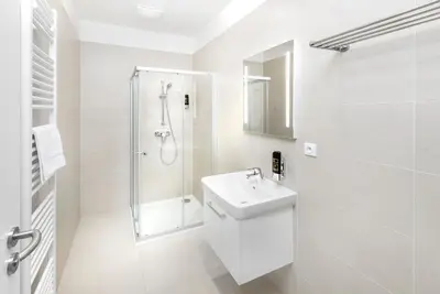 a white bathroom with a shower and a sink at DownTown Suites Belohorska in Prague