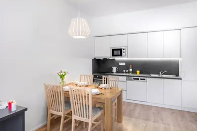a kitchen with a wooden table and chairs in a kitchen at DownTown Suites Belohorska in Prague