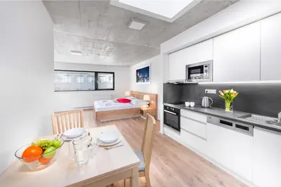a kitchen with white cabinets and a table with fruits on it at DownTown Suites Belohorska in Prague