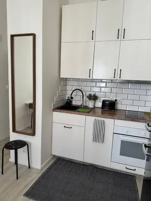 a kitchen with white cabinets and a sink and a mirror at Homelike Prague Apartment in Prague