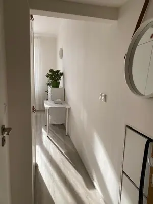 a white hallway with a mirror and a table at Homelike Prague Apartment in Prague