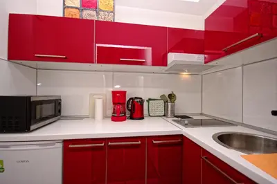 a kitchen with red cabinets and a sink and a microwave at Cozy Gardens Apartments in Prague in Prague