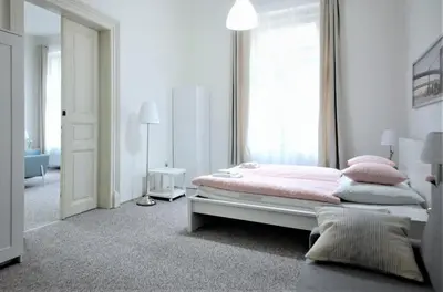 a white bedroom with a pink bed and a window at Aparthotel Wenceslas in Prague
