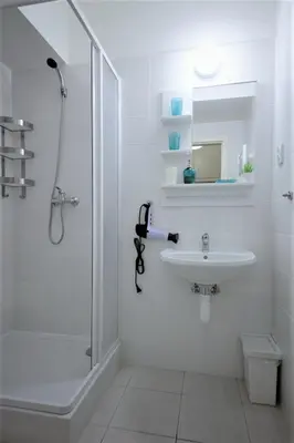 a white bathroom with a shower and a sink at Aparthotel Wenceslas in Prague
