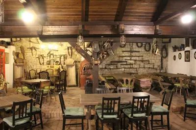 a restaurant with tables and chairs and a stone wall at Hotel Černý kůň in Louny