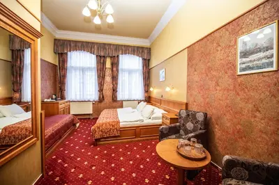 a hotel room with two beds and a chair at Old Prague Hotel in Prague