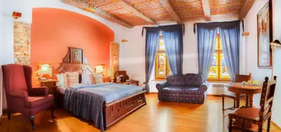 a bedroom with a bed and a chair and two windows at The King Charles in Prague