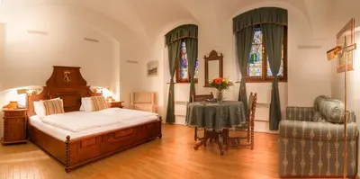 a bedroom with a bed and a table and two windows at The King Charles in Prague