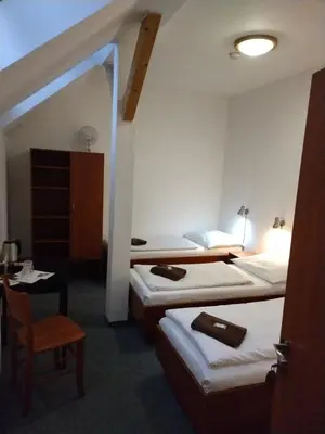 a hotel room with two beds and a chair at Beta Pension in Prague
