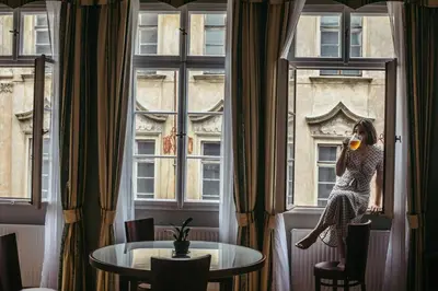 a woman sitting in a window drinking a glass of wine at Residence Thunovska in Prague