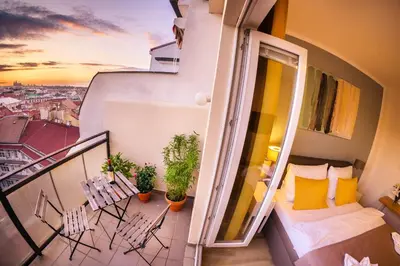 a balcony with chairs and a bed and a view of a city at Michal&Michael’s Central Apartments in Prague