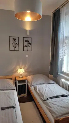 a bedroom with two beds and a lamp and a window at Atmospheric Quiet Apartment in Prague