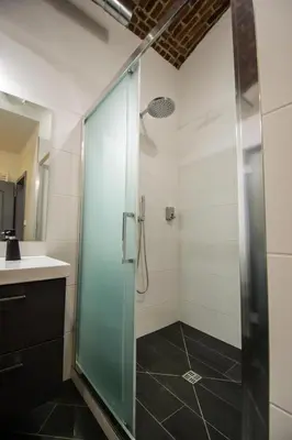 a bathroom with a glass shower and a sink at Brooklyn Sauna Apt by Ruterra in Prague