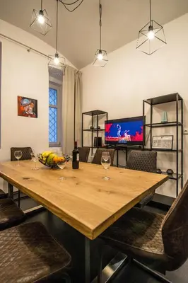 a dining room with a wooden table and a television at Brooklyn Sauna Apt by Ruterra in Prague