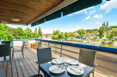 a table on a deck with a view of a river at Botel Vodnik in Prague