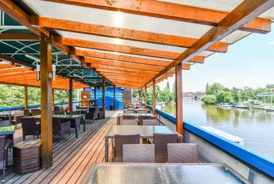 a boat deck with tables and chairs on a river at Botel Vodnik in Prague