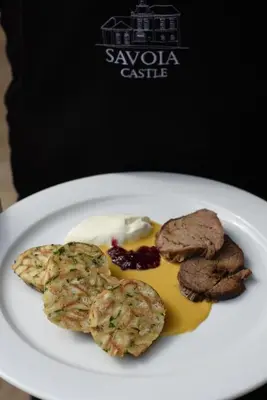 a plate of food with meat and sauce on it at Savoia Castle in Škvorec