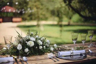 a wooden table with a flower arrangement and wine glasses at Savoia Castle in Škvorec