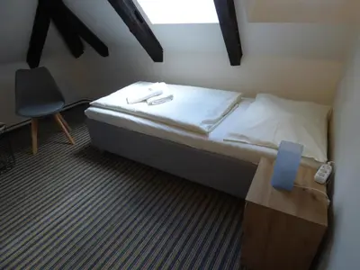 a small bedroom with a bed and a chair at Hotel Svornost in Prague