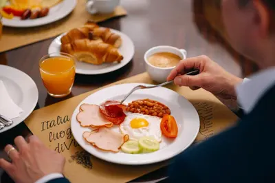 a person sitting at a table with a plate of breakfast food at Hotel Leon D´Oro in Prague