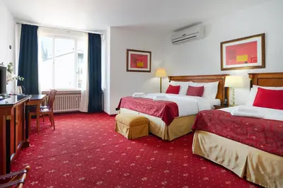 a hotel room with two beds and a desk at Hotel Leon D´Oro in Prague