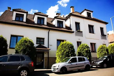two cars parked in front of a large white house at Hotel Excellent in Prague