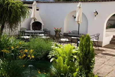 a patio with tables and chairs and a pond at Hotel Excellent in Prague
