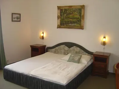 a bedroom with a bed with two nightstands and a painting at Hotel Excellent in Prague