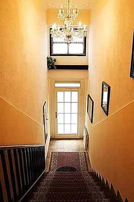 a hallway with a chandelier and a door with a window at Hotel Excellent in Prague