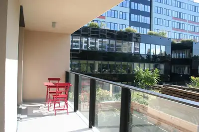 a balcony with red chairs and a red table and a building at Karlín Apartment in Prague