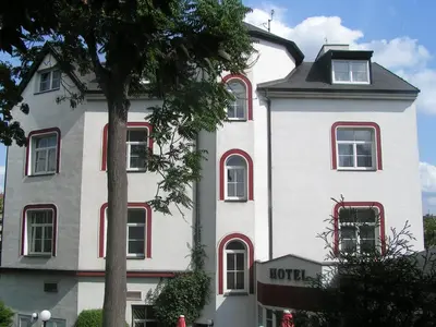 a white building with red windows and a tree at Hotel Jerabek in Prague