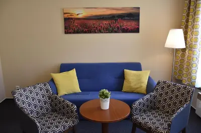 a living room with a blue couch and two chairs at Aparthotel Austria Suites in Prague