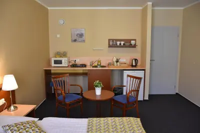 a room with a bed and a kitchen with a table and chairs at Aparthotel Austria Suites in Prague