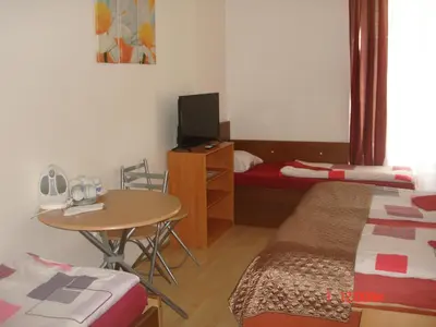 a small room with a small table and a bed and a desk at Pension Easy Journey in Prague