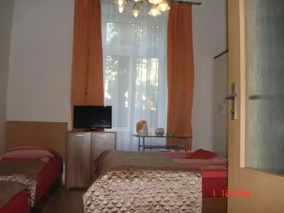 a bedroom with two beds and a window with a television at Pension Easy Journey in Prague