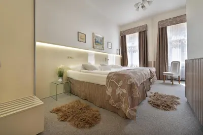 a bedroom with a bed and a chair and windows at Anette Hotel in Prague
