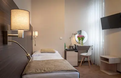 a bedroom with a bed and a desk and a lamp at Pytloun Kampa Garden Hotel Prague in Prague