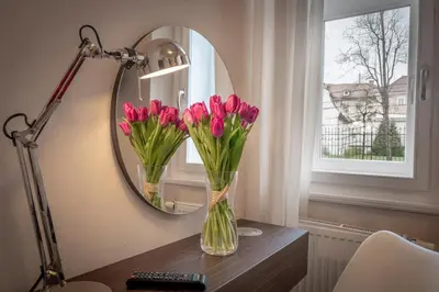 a vase of flowers on a table in front of a mirror at Pytloun Kampa Garden Hotel Prague in Prague