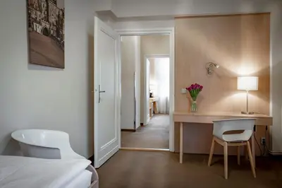 a hotel room with a bed and a desk and chairs at Pytloun Kampa Garden Hotel Prague in Prague