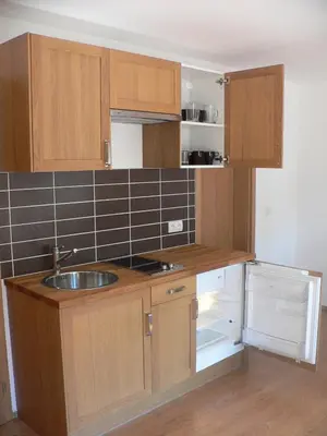 a small kitchen with wooden cabinets and a sink at Penzion Speller in Vysoký Újezd