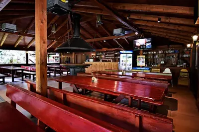 a restaurant with wooden benches and a bar at Apartmány & Kemp Sázavský ostrov in Sázava