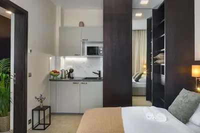 a bedroom with a white bed and a kitchen at Wenceslas Hotel & Apartments in Prague