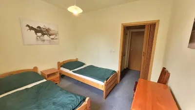 a bedroom with two beds and a table and a mirror at Pension Patanka in Prague
